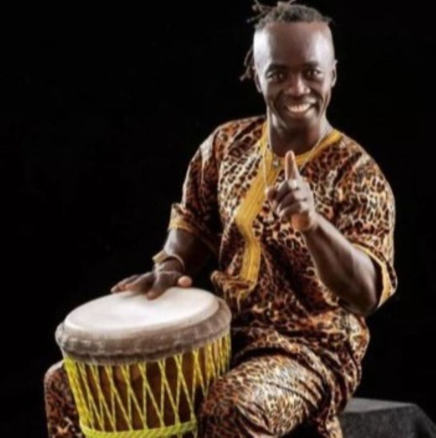 Epizo smiling while playing an African djembe